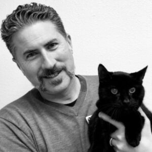 black and white photo of male veterinarian holding a black cat